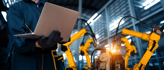 MLP Engineer use advanced robotic software to control industry robot arm in factory. Automation...