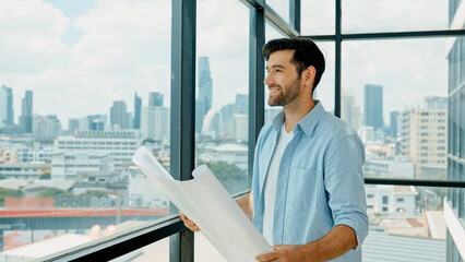 Professional architect engineer or male worker in casual outfit looking at skyscraper and city view...