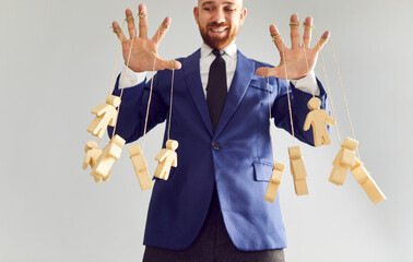 Bossy business man company owner on grey background has fun moving fingers pulling strings with...