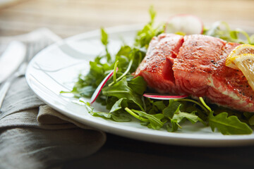 Food, fish protein and salad for health with nutrition, lunch plate and wellness with pescatarian diet. Salmon, rocket and plant leaves on table with cholesterol for vitamin c benefits and digestion