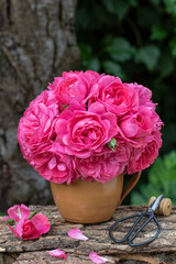 Blumenstrauß mit pink Rosen Roisarium Uetersen in rustikaler Vase im Sommergarten	
