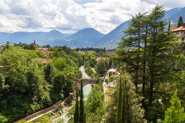 River passer promenade in Merano with mountain panorama and bridge, South Tyrol, Italy