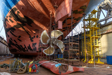 Cargo vessel in dry dock on ship repairing yard. Variable pitch propeller and rudder. Welder...