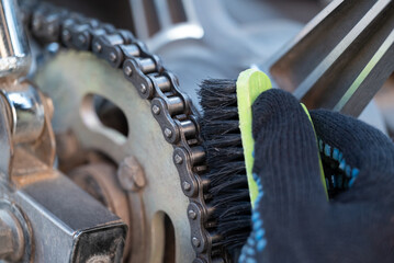 Cleaning motorbike chain with a brush. Close up of a motorcycle service worker cleaning chain of a...