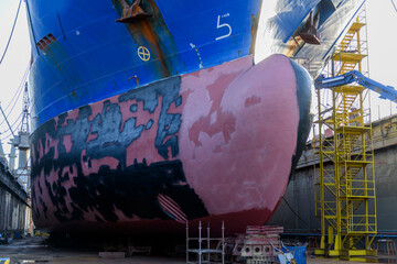 Cargo vessel in dry dock on ship repairing yard. Bulbous bow.