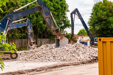 demolition company mechanical shovels on a job site with rubble remains of building shot in...