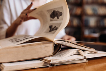 Close-up opened book on the table in library. Blurry bookshelf background for education and publication concept. Back to school. Bookshelves in school study class room background. © Валерия Стоганенко