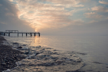Small sea waves splashing at the beach with pebbles at sunset, selective focus