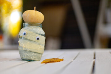 jar decor ghost mummy with halloween pumpkin on autumn bokeh background