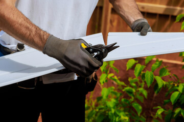 Craftsman cuts vinyl siding panel to desired size before installing it on facade of building