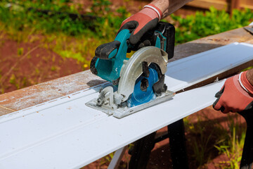 Before installing vinyl siding panels on facade of craftsman's home, he cuts them to desired size