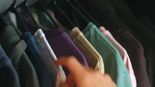 Close up - Man hands taking t-shirt in the wardrobe at sunny morning at home. Morning get ready for work concept.