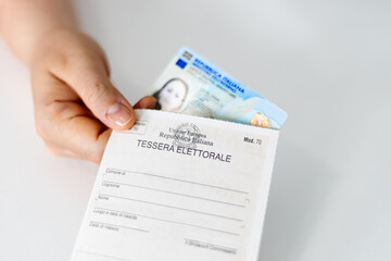 Hand holding Italian Identity Card (ID) and Electoral Card (Tessera Elettorale)