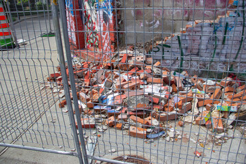 a collapsed wall behind a fence