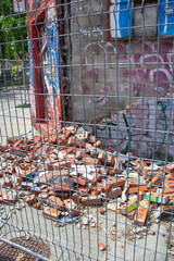 a collapsed wall behind a fence