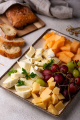 Cheese plate with different cheese, grapes and melon.
