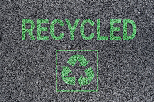 Sign and inscription "Recycled" on a surface made from recycled car tires, showcasing a modern material in a close-up texture-filled frame.