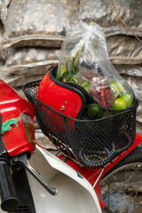 A motor bike red helmet baskets  a bag of green lemons and chilis