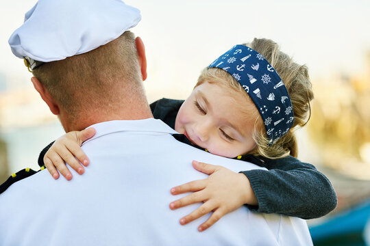 Hug, happy kid and reunion with father from navy, service and comfort on dock. Man, young daughter and care outdoors for welcome, love and happiness for return from work, deployment and uniform
