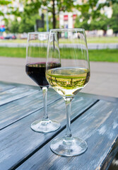 Red wine and white wine glass on restaurant table, wineglasses dinner on restaurant summer terrace