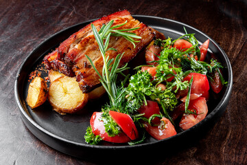 A plate of grilled pork meat, herbs, and vegetables
