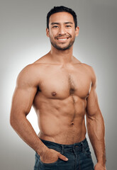 Fototapeta premium Man, portrait and happy in studio with abs or muscles, shirtless and grey background with model or bodybuilder. Jeans, strong chest and Asian male person on backdrop, confidence with six pack
