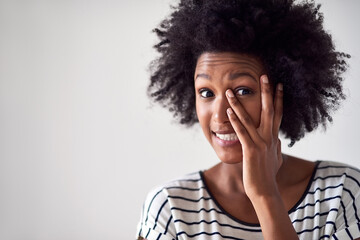 Portrait, African woman and peeking with hand over eye in studio with nervous emoji on mock up space. Female person, gen z and cover face or hide for embarrassed with fear by white background