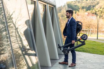 Businessman with backpack enters office building with his electric scooter, sustainable city commute