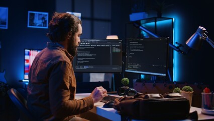 Freelancing software programmer arriving in personal office at home, resuming work on coding. Self...