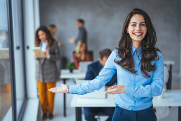 A delighted Caucasian businesswoman with open arms ready for teamwork stands in a bustling,...