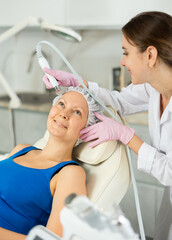 Professional female cosmetologist doing hydrafacial procedure in modern cosmetology clinic. Doctor...