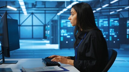 IT engineer looking at PC screen, working in network security data center, ensuring optimal...