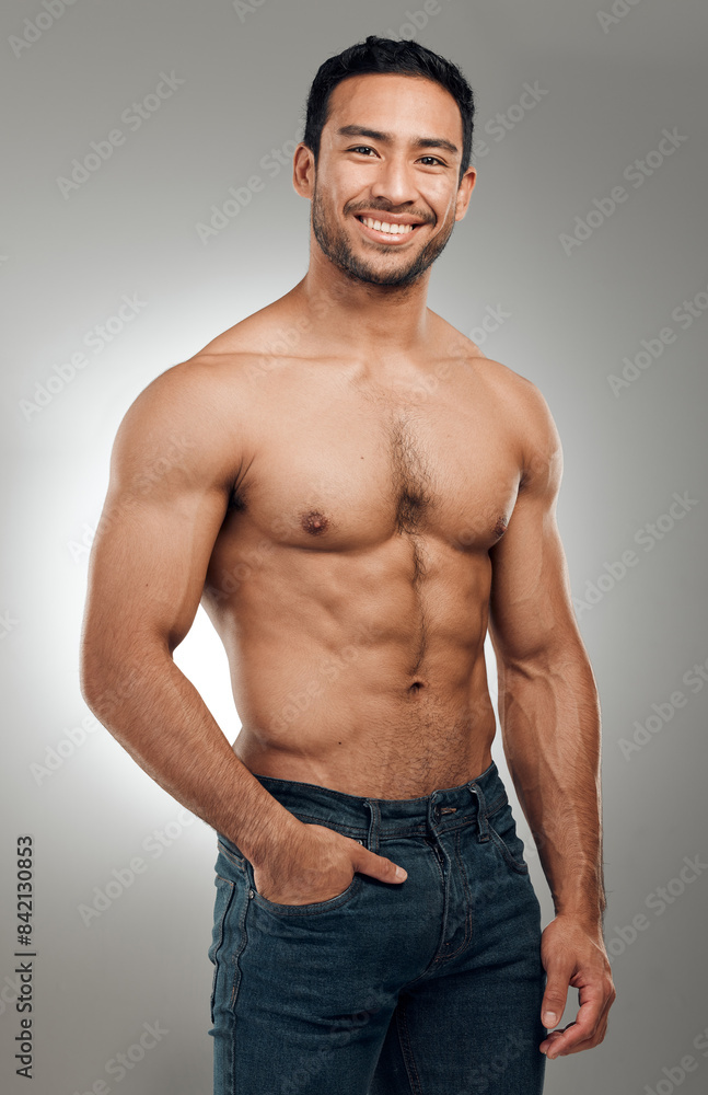 Sticker Man, portrait and smiling in studio with abs or muscles, shirtless and grey background with model or bodybuilder. Jeans, strong chest and Asian male person on backdrop, confidence with six pack