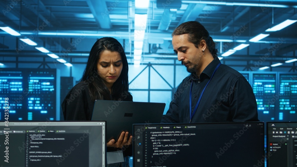 Aufkleber technicians working in high tech server hub, analyzing data on laptop to ensure seamless data flow. 
