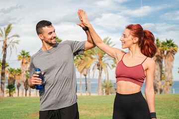 Sporty couple smiles and high-fives after achieving a milestone during their cardio workout. Strong...