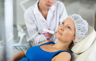 Woman getting facial radio wave lifting skin tightening procedure in beauty salon. RF-lifting...