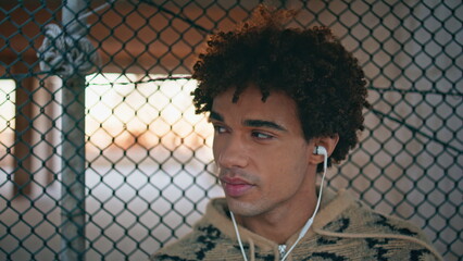Relaxed student listening headphones music in urban setting closeup. Curly guy