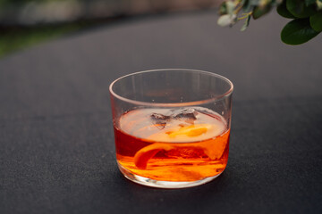 bright orange cocktail in low rocks glass on black tablecloth