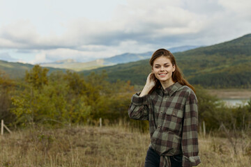 Woman embracing nature A fashionable traveler in plaid shirt posing in a picturesque mountain field
