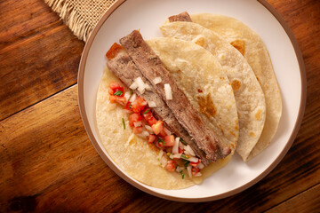 Arrachera Tacos. Marinated beef steak served in a wheat tortilla on a mexican clay plate. Street food from Mexico, traditionally accompanied with cilantro, onion and spicy sauce or guacamole.