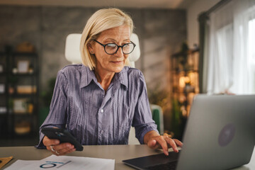 Mature senior woman work from home and use mobile phone and laptop
