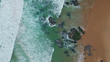 Rocky stones break waves display of nature power aerial view. Sea meeting beach