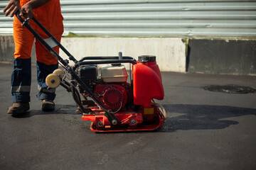 Asphalt paving machine. Worker compacts roadway. Repair of road.