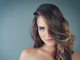 Naklejka premium Portrait, hair care and woman with shine, wellness and dermatology on grey studio background. Face, person and cosmetics for glow, keratin and luxury treatment with shampoo, texture and healthy scalp