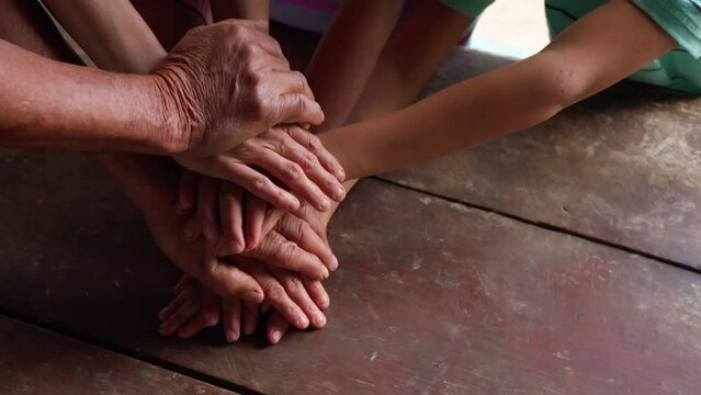 The family's hands are placed on top of each other on a table as a symbol of unity and strength.