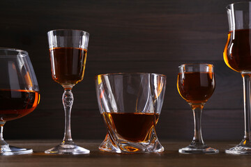 Different delicious liqueurs in glasses on wooden table