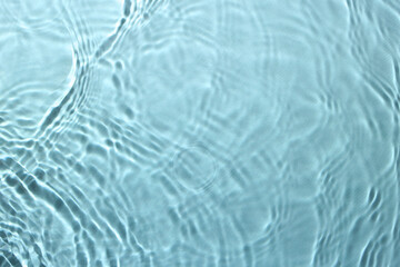Rippled surface of clear water on light blue background, top view