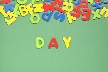 Word Day made of magnetic letters on green background, flat lay. Learning alphabet