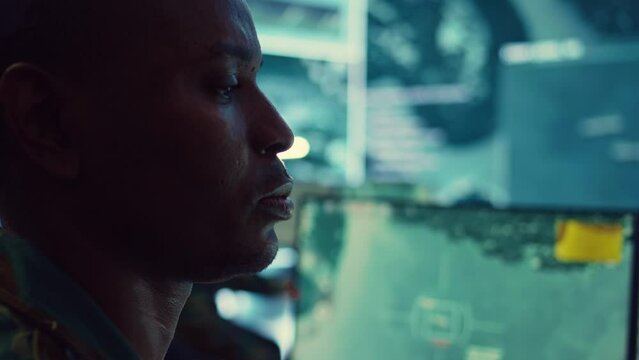 Lieutenant colonel gathering intelligence from federal radar systems, working with his crew in military command control room. Examining satellite imagery for reconnaissance mission. Camera B.