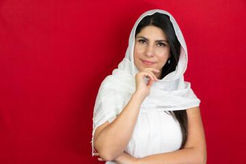 Portrait of a woman with a white scarf in the studio. middle eastern young woman red background